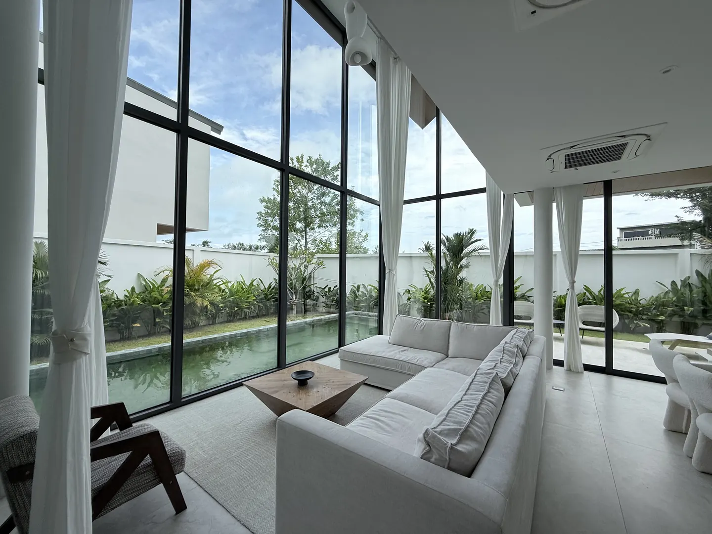 Double-height living room with floor-to-ceiling glass onto the pool